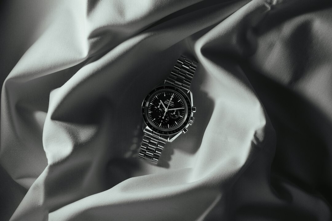 Vintage chronograph watch resting on a dark wood table beside a leather box