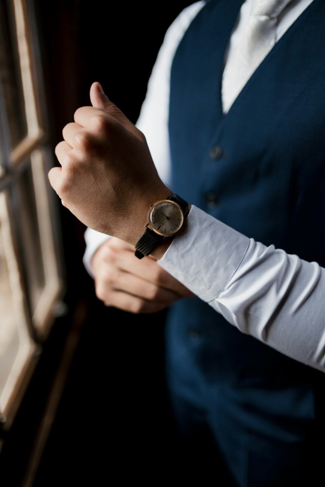 Elegant man's wrist wearing a slim gold dress watch with a cufflink