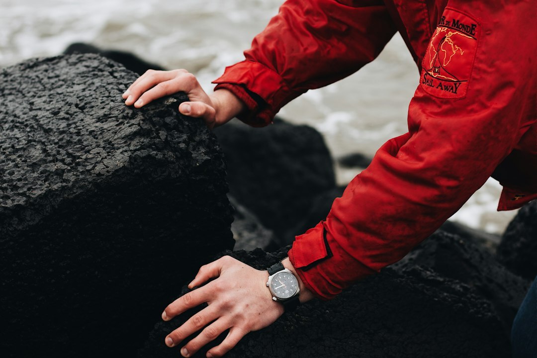 Man's wrist wearing a luxury steel dive watch near the ocean